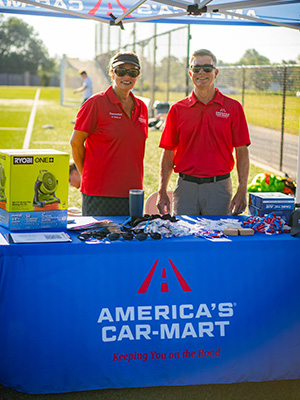 Two Car-Mart associates standing at youth soccer clinic booth and tent.