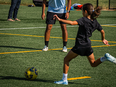 Youth female kicking yellow soccer ball